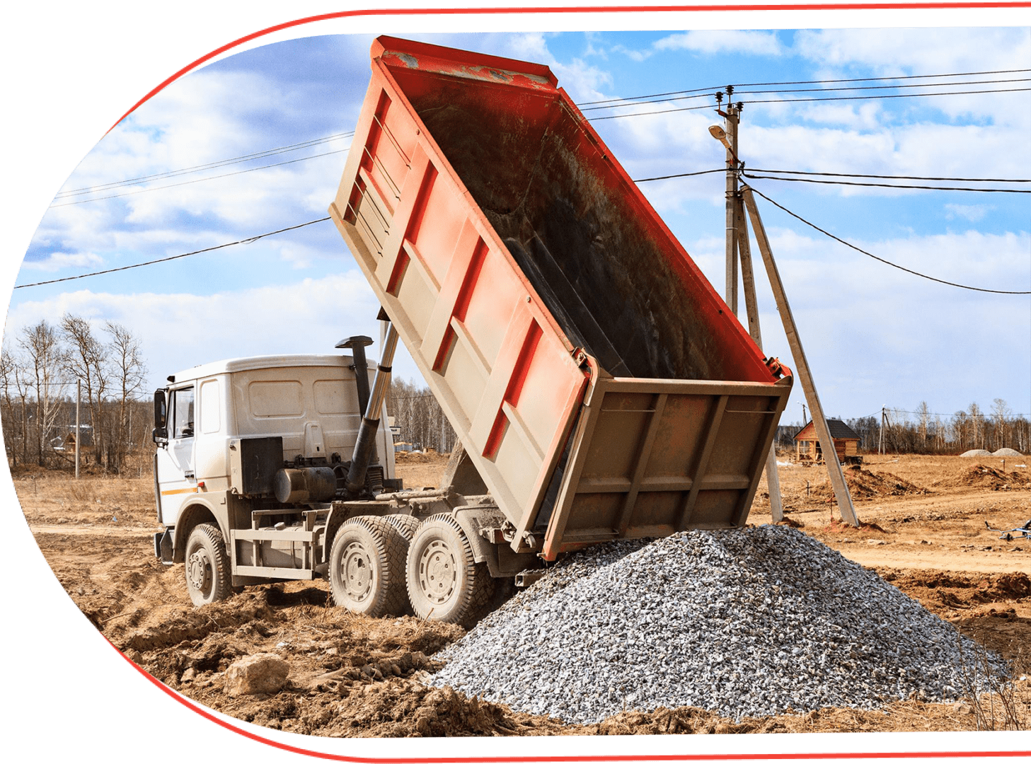 A dump truck dumping gravel on the side of a road.